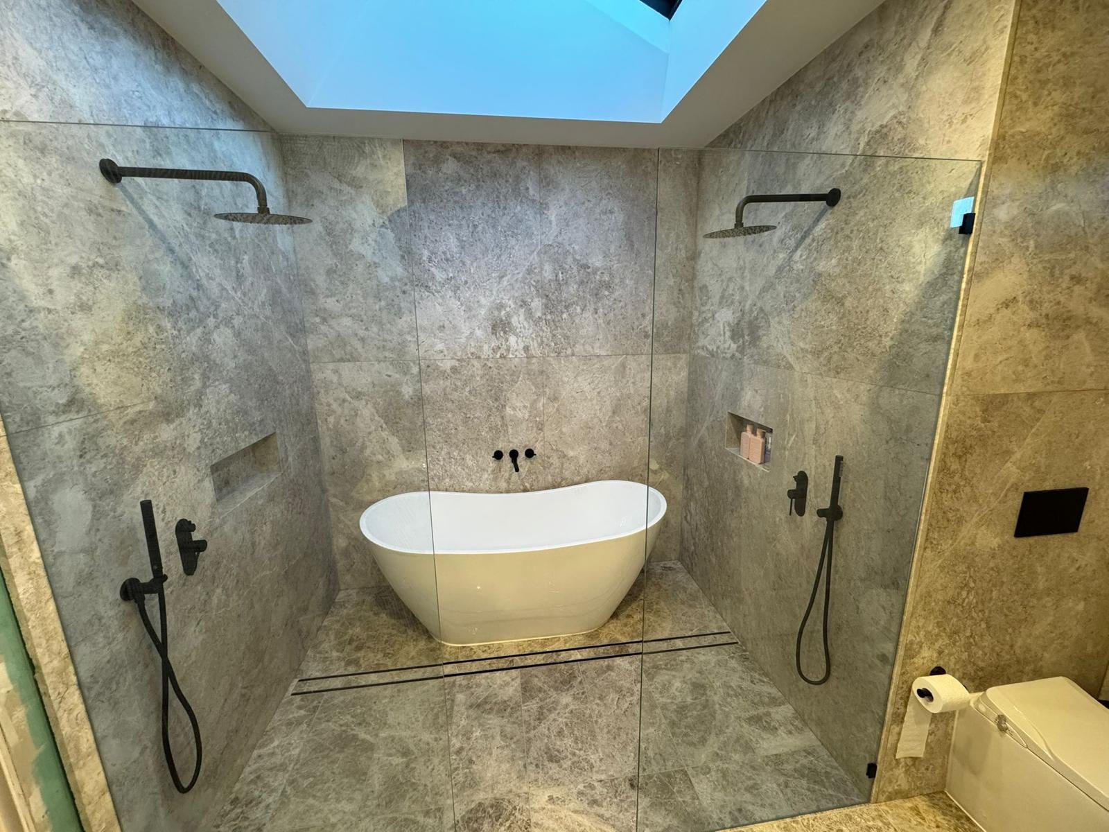 Freestanding bath between twin showers with skylight