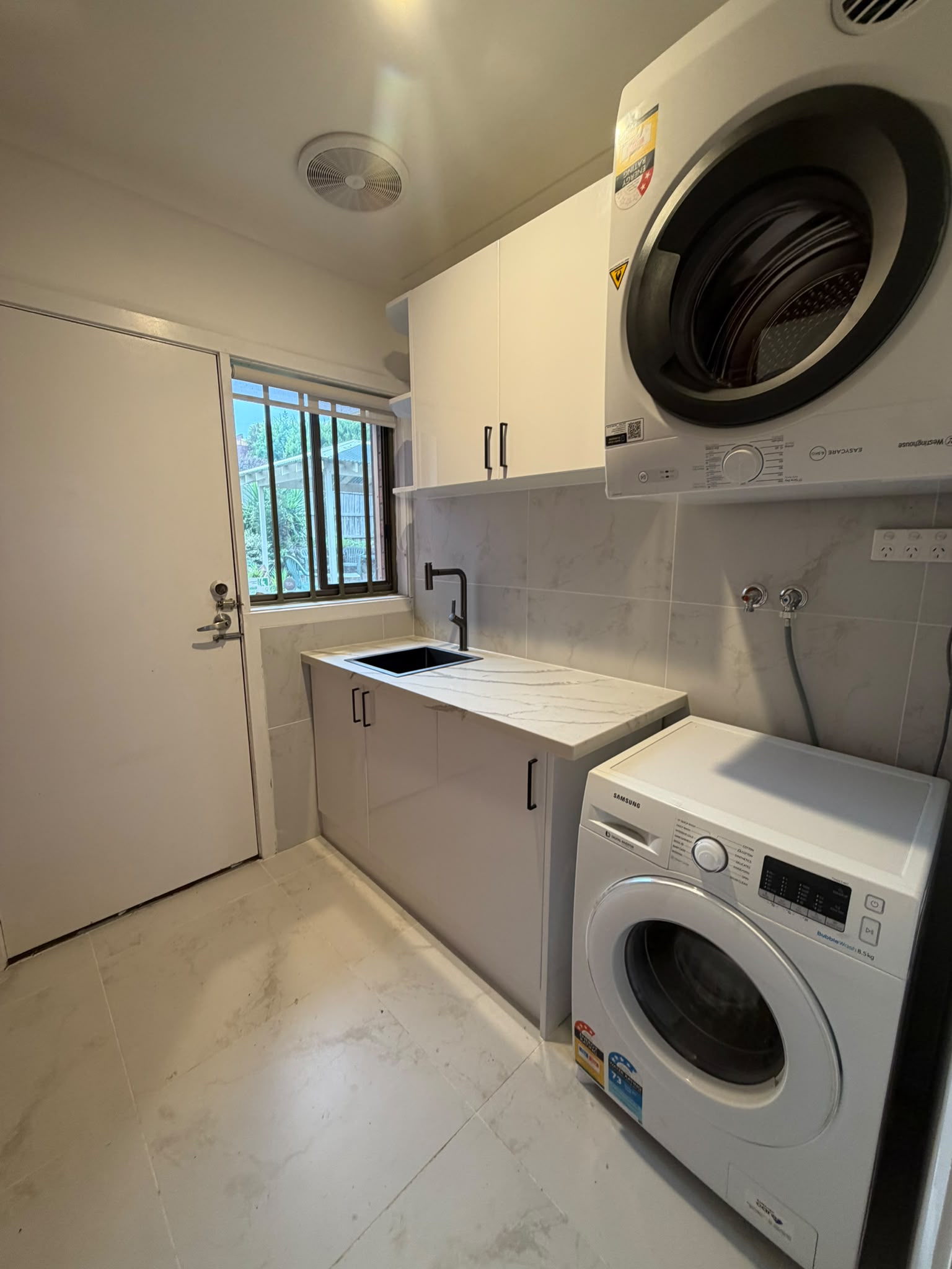 Laundry bench with black sink, stone top and garden window